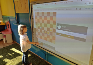 Dziewczyna ćwiczy ruchy króla na tablicy interaktywnej
